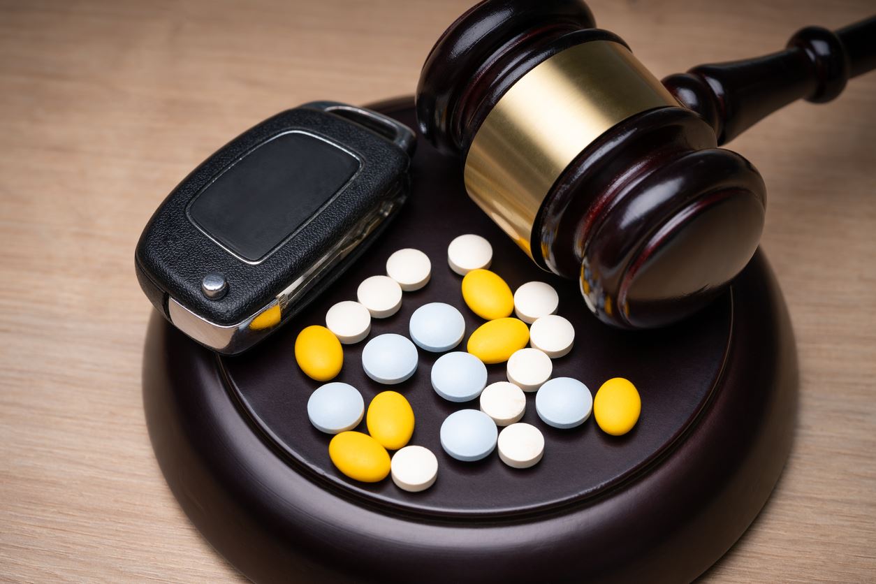 car keys, pills, and judge gavel on desk