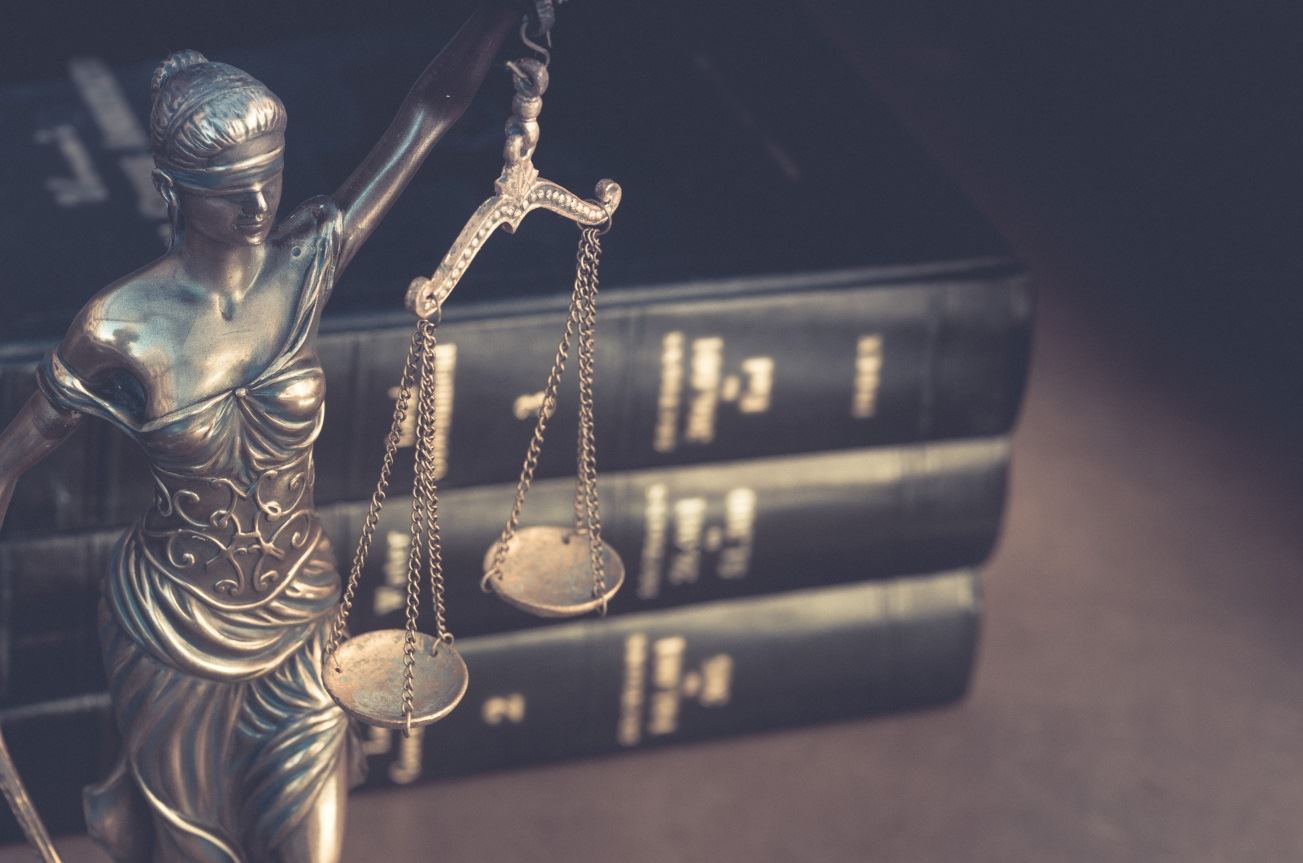 Scales of justice statue next to law book