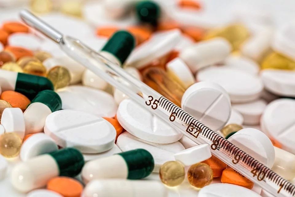 This picture shows a needle and various pills.